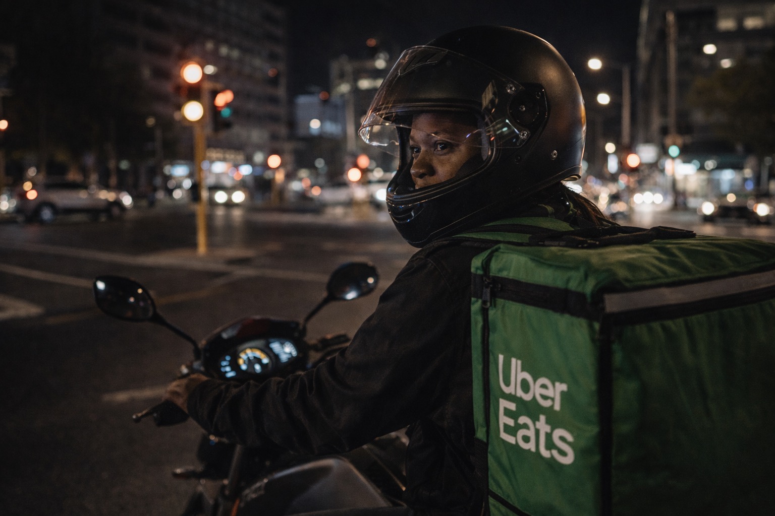 An Uber Eats rider in helmet riding through the CBD at night