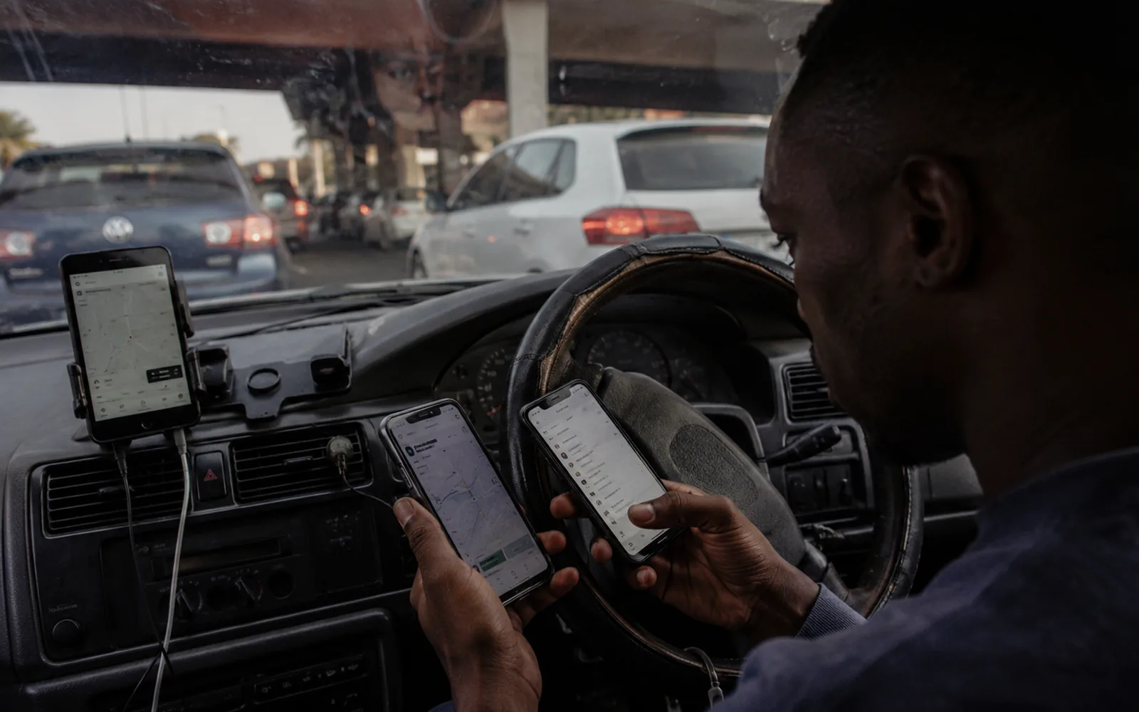 A driver at the wheel with two platform phones mounted on the dash