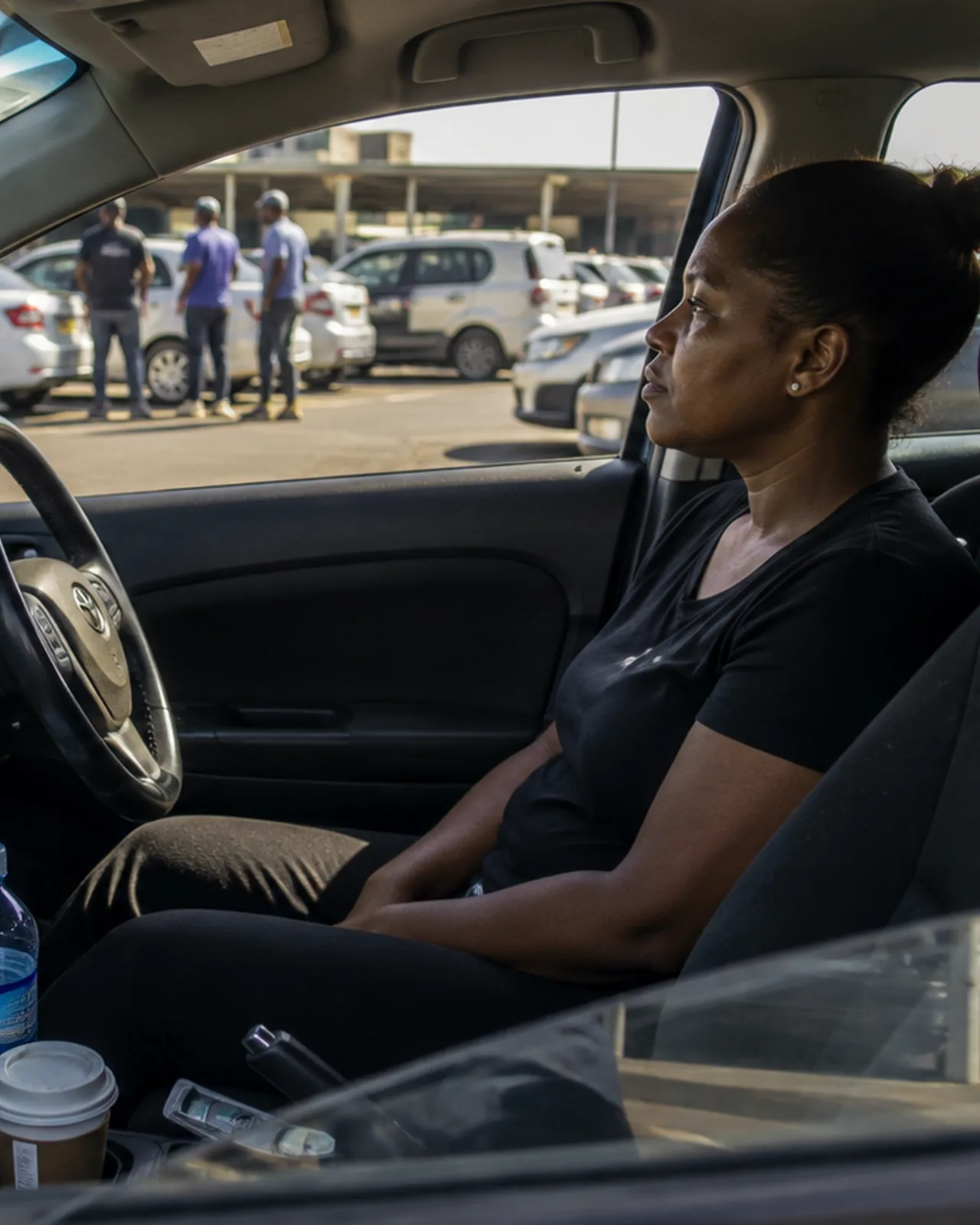 A driver in her car in a lot at the end of a shift
