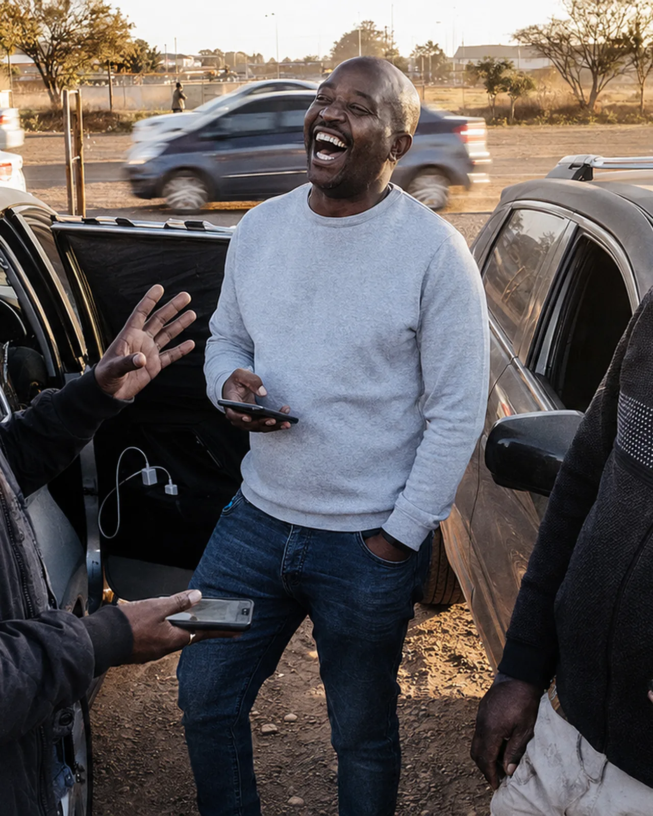 A driver talking and laughing with others beside a car