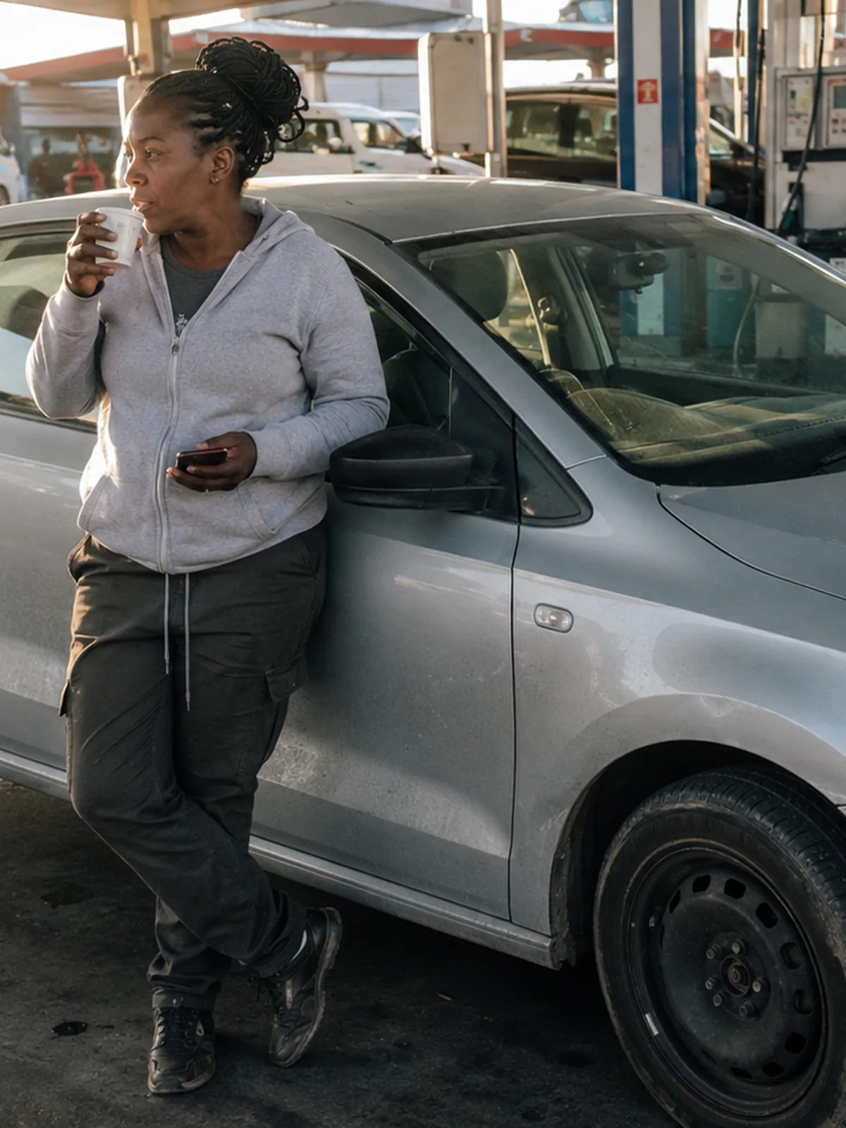A driver leaning on her car at the forecourt